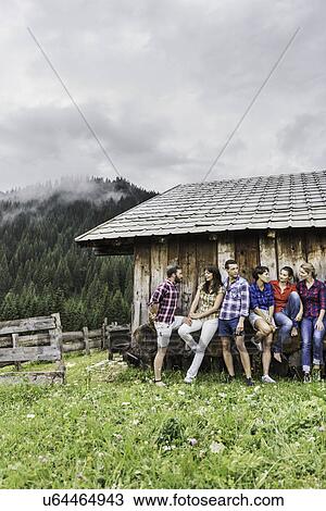 Group of friends chatting behind wooden shack, Tirol, Austria View Large Photo Image Stock Image - Group of friends chatting behind wooden shack, Tirol, Austria. Fotosearch