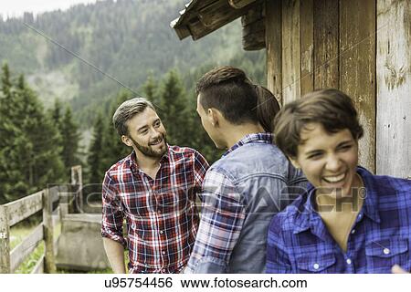 Stock Photograph - Group of friends chatting behind wooden shack. Fotosearch