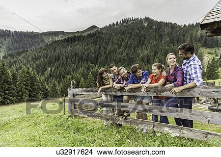 Picture - Group of friends leaning on wooden fence, Tirol, Austria. Fotosearch