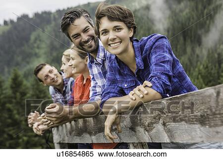 Stock Photography - Group of friends leaning on wooden fence, Tirol, Austria. Fotosearch