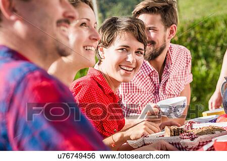 Stock Photograph - Group of friends sitting for breakfast outdoors. Fotosearch