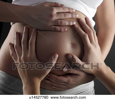Stock Image - Hands on pregnant woman's belly. Fotosearch