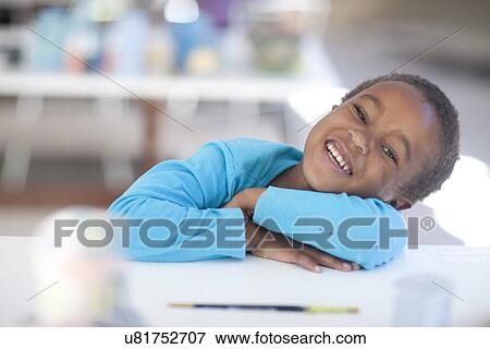 Stock Photo - Happy girl arms crossed on table. Fotosearch