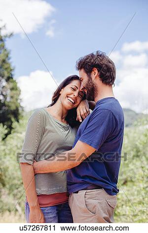 Stock Image - Happy mid adult couple hugging outdoors. Fotosearch