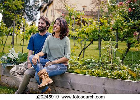 Happy mid adult couple sitting in garden View Large Photo Image Stock Photo - Happy mid adult couple sitting in garden. Fotosearch