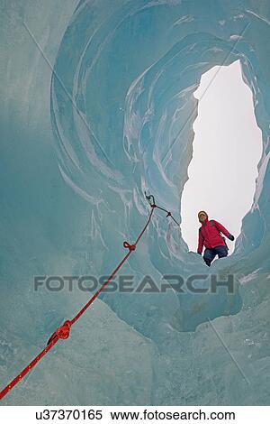 Stock Photography - Ice climber looking down ice cave Fox Glacier, South Island, New Zealand. Fotosearch