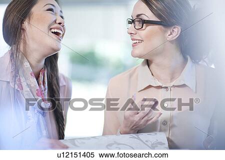 Stock Photography - Interior designer and client with wallpaper book. Fotosearch
