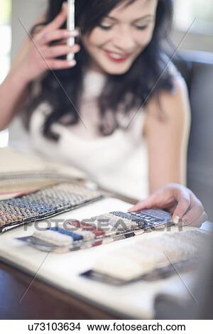 Picture - Interior designer making call and looking at textile swatches. Fotosearch