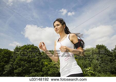 Stock Image - Jogger listening to mp3 player with earphones. Fotosearch