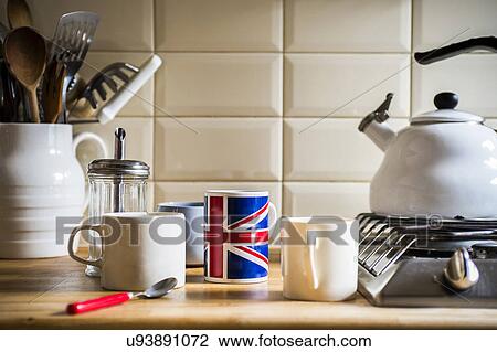 Stock Image - Kitchen counter with jug of utensils and coffee mugs. Fotosearch