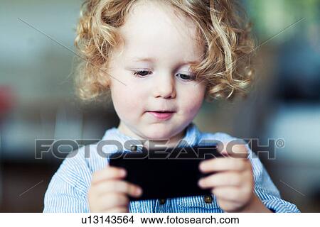 Male toddler looking at mobile phone View Large Photo Image Picture - Male toddler looking at mobile phone. Fotosearch