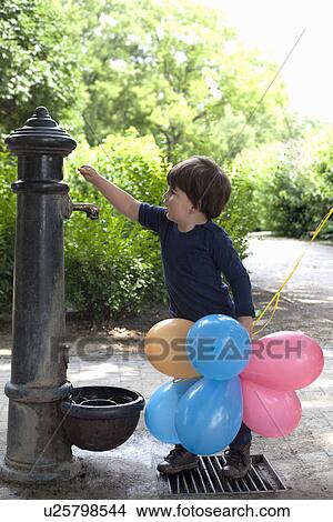 Picture - Male toddler looking curiously at garden water pump. Fotosearch