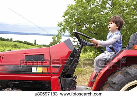 Male toddler pretending to drive tractor in garden View Large Photo Image Stock Image - Male toddler pretending to drive tractor in garden. Fotosearch