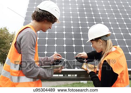 Stock Photo - Man and woman working on photo voltaic panels. Fotosearch