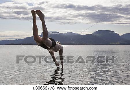 Stock Photo - Man diving into water, Aure, Norway. Fotosearch