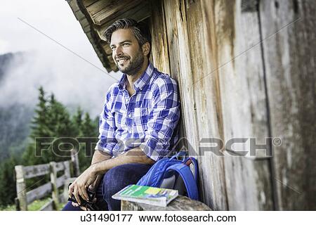 Man enjoying the view from wooden shack, Tirol, Austria View Large Photo Image Stock Photo - Man enjoying the view from wooden shack, Tirol, Austria. Fotosearch