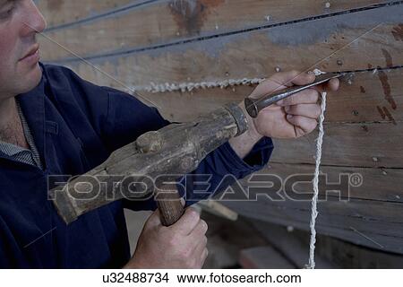 Man hammering string into boat in workshop View Large Photo Image Picture - Man hammering string into boat in workshop. Fotosearch