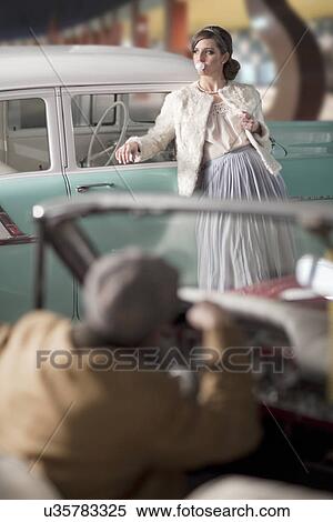 Man looking at woman leaning on vintage car View Large Photo Image Stock Photography - Man looking at woman leaning on vintage car. Fotosearch
