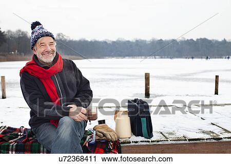 Man sitting on pier having hot drink View Large Photo Image Stock Image - Man sitting on pier having hot drink. Fotosearch