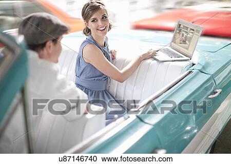 Man watching woman use laptop in back seat of convertible View Large Photo Image Stock Image - Man watching woman use laptop in back seat of convertible. Fotosearch