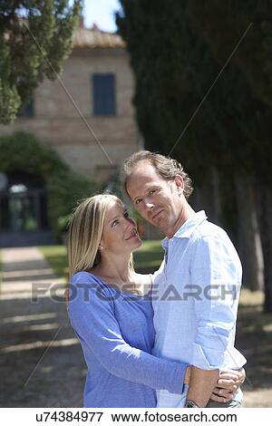 Stock Photo - Mature couple standing in garden hugging. Fotosearch