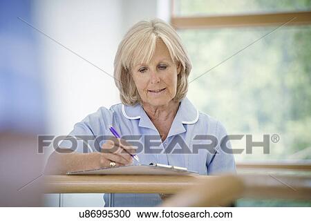 Mature female nurse in hospital corridor with clipboard View Large Photo Image Stock Image - Mature female nurse in hospital corridor with clipboard. Fotosearch