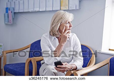 Mature female patient with mobile phone in hospital waiting room View Large Photo Image Stock Photograph - Mature female patient with mobile phone in hospital waiting room. Fotosearch