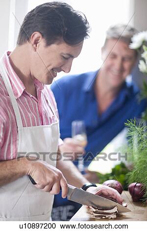 Mature man chopping red onion, man in background View Large Photo Image Stock Image - Mature man chopping red onion, man in background. Fotosearch