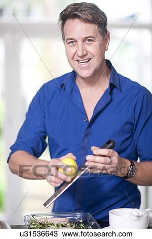 Stock Image - Mature man grating lemon zest. Fotosearch