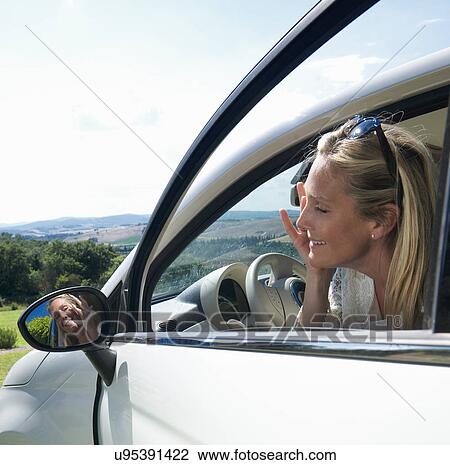 Mature woman applying make up in mirror of car View Large Photo Image Stock Image - Mature woman applying make up in mirror of car. Fotosearch