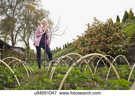 Stock Photo - Mature woman standing in vegetable garden. Fotosearch