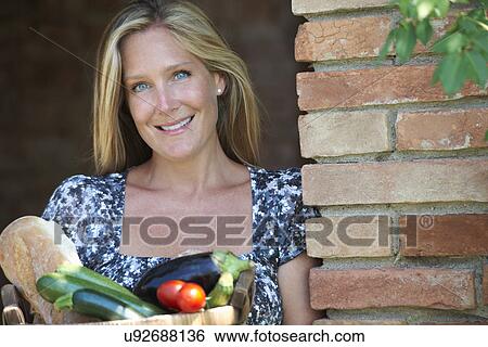 Mature woman standing outside with basket of organic food View Large Photo Image Stock Photograph - Mature woman standing outside with basket of organic food. Fotosearch