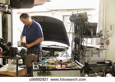 Mechanic repairing car in workshop View Large Photo Image Stock Image - Mechanic repairing car in workshop. Fotosearch