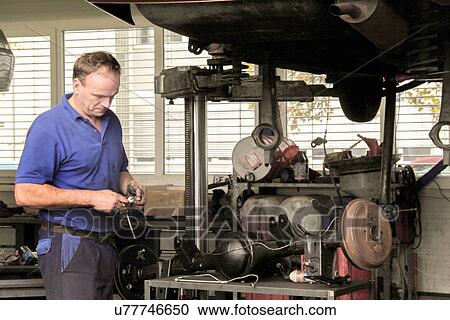Stock Image - Mechanic repairing car in workshop. Fotosearch