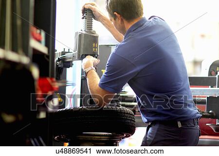 Mechanic repairing wheel in workshop View Large Photo Image Stock Image - Mechanic repairing wheel in workshop. Fotosearch
