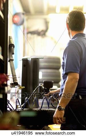 Stock Photography - Mechanic repairing wheel in workshop. Fotosearch