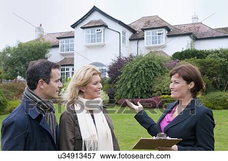 Mid adult couple and female estate agent outside house View Large Photo Image Stock Photo - Mid adult couple and female estate agent outside house. Fotosearch
