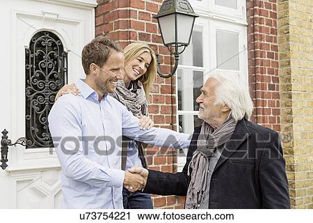 Mid adult couple by front door, senior man shaking hands View Large Photo Image Stock Image - Mid adult couple by front door, senior man shaking hands. Fotosearch
