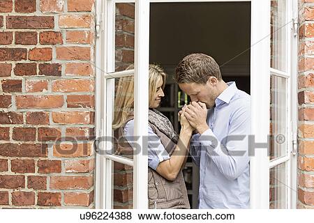 Mid adult couple by window, man kissing woman's hands View Large Photo Image Stock Photo - Mid adult couple by window, man kissing woman's hands. Fotosearch