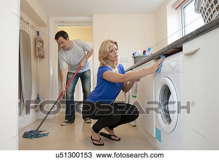 Stock Image - Mid adult couple cleaning kitchen in new home. Fotosearch
