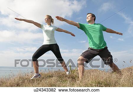 Stock Image - Mid adult couple exercising on cliff top, Thurlestone, Devon, UK. Fotosearch