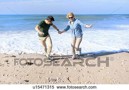 Stock Photography - Mid adult couple fooling around on beach, Thurlestone, Devon, UK. Fotosearch