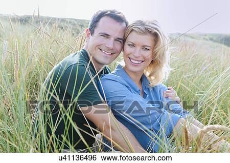 Stock Photograph - Mid adult couple in sandunes, Thurlestone, Devon, UK. Fotosearch