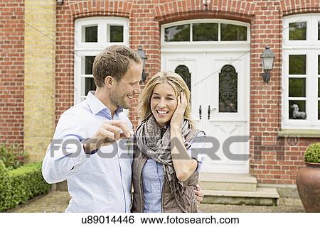 Mid adult couple outside house, man holding key View Large Photo Image Stock Photograph - Mid adult couple outside house, man holding key. Fotosearch