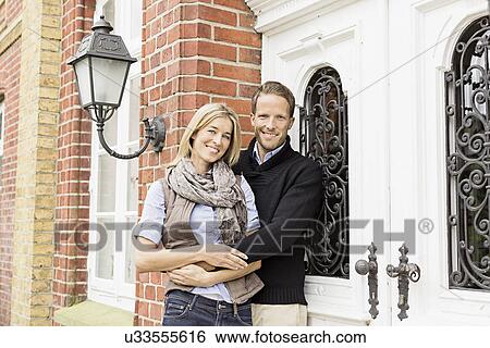 Stock Photograph - Mid adult couple outside house. Fotosearch