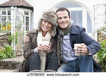 Stock Image - Mid adult couple outside new house. Fotosearch