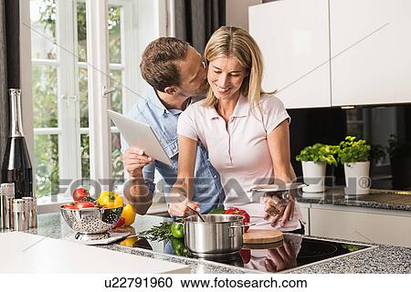 Mid adult couple preparing food, man with digital tablet View Large Photo Image Stock Image - Mid adult couple preparing food, man with digital tablet. Fotosearch
