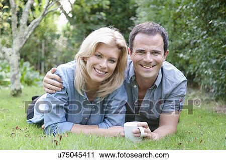 Mid adult couple relaxing in garden View Large Photo Image Stock Image - Mid adult couple relaxing in garden. Fotosearch