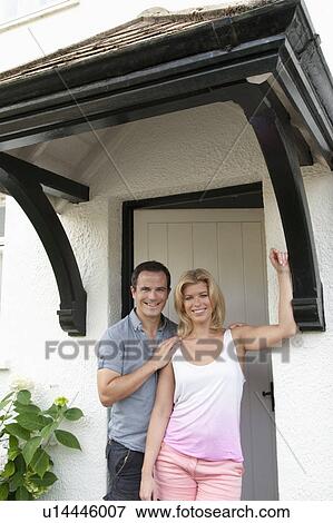 Mid adult couple standing at front door of new home View Large Photo Image Stock Photo - Mid adult couple standing at front door of new home. Fotosearch
