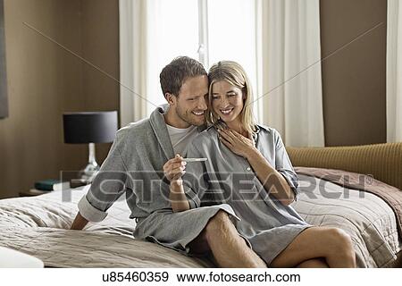 Stock Photo - Mid adult couple, woman holding pregnancy test. Fotosearch